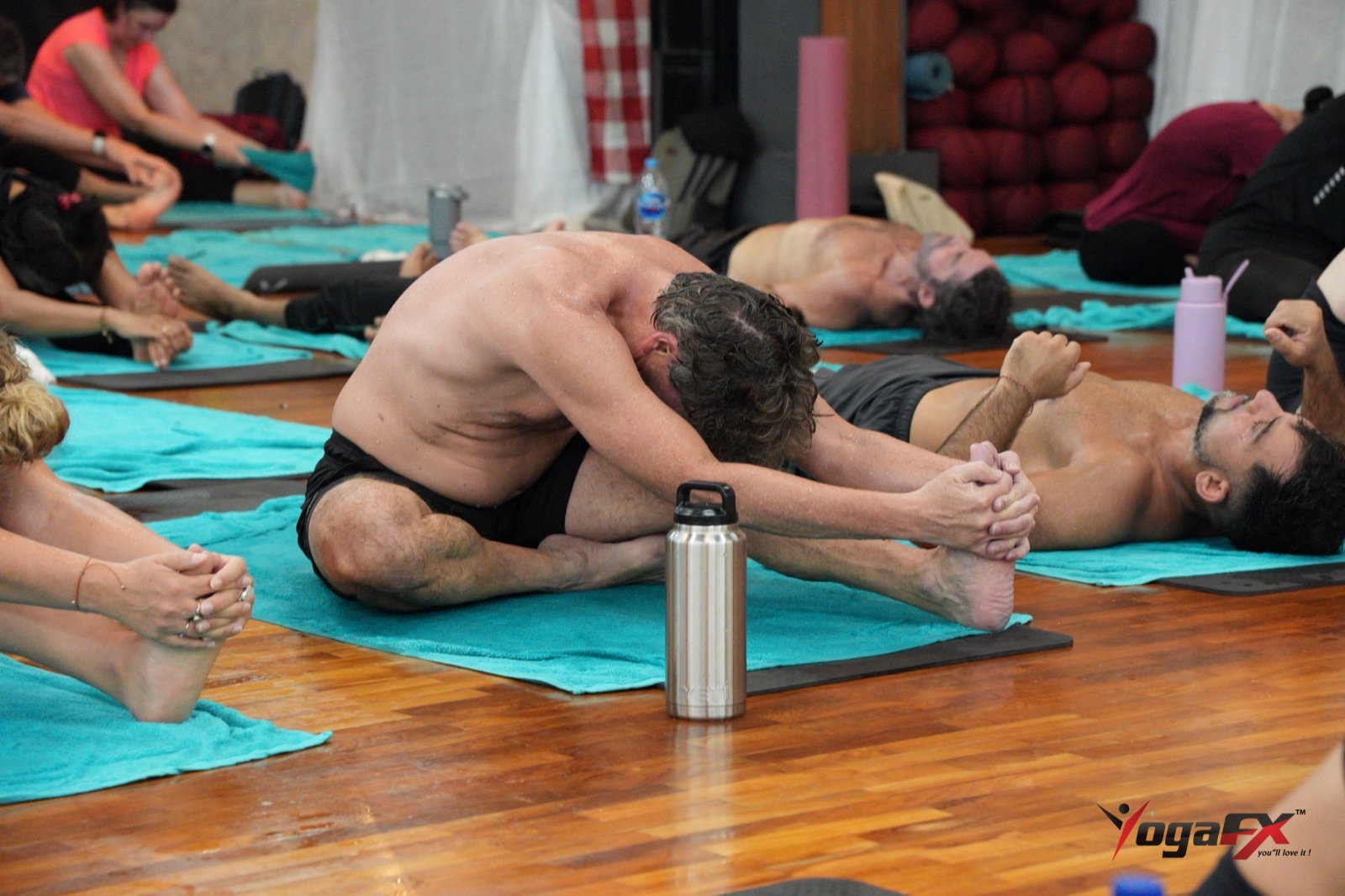 Men in their forties folding forward in a seated stretch during the floor series, a gentle starting point for yoga for men over 40